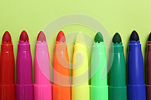 Set of felt tip pens on light green background, flat lay