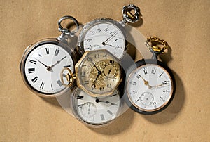 Set of five antique gold and silver pocket watches on beige background. Retro mechanical watch with white dials, hands