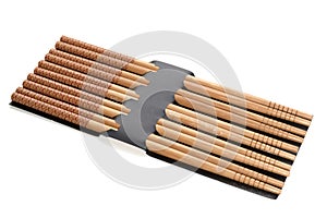 A set of five pairs of wood wooden chopsticks  against a white backdrop