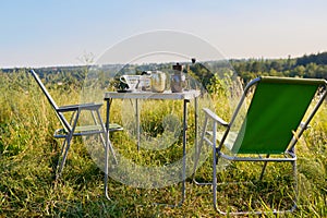 Set of folding furniture for camping, table and chair, summer nature of wild meadow
