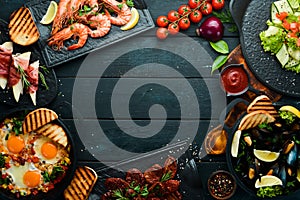 Set of food from meat, fish and salads on black background. Top view.