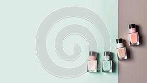 A set of four bottles of nail polish in different colors, green, white, pink and brown shades, top view on a two-tone