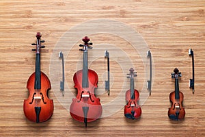 Set of four toy string musical orchestra instruments: violin, cello, contrabass, viola on a wooden background. Music concept.