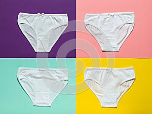 Set of four white women`s panties on a multi-colored background. Flat lay.