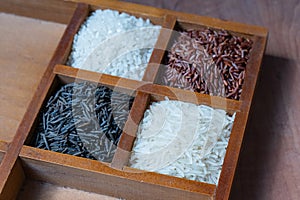 Set of four wooden cells with red, white and black rice, bassmati rice background