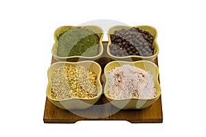 Set of fragrant consists of spices in ceramic cups salt, peppercorn, dried garlic and ground parsley on a wooden tray isolated