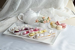 Set of French dessert eclairs with colorful icing and cup of coffee on the table