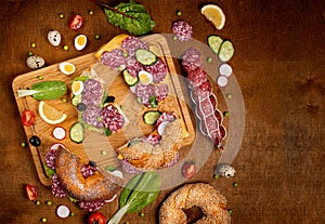 Set of fresh bagels with Salami, radish, cucumber. Top view. Wooden background