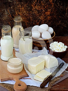 Set of fresh dairy products on wooden background: milk cheese cottage yogurt egg mozzarella ryazhenka feta.