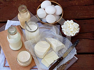 Set of fresh dairy products on wooden background: milk, cheese cottage yogurt, egg, mozzarella ryazhenka feta.