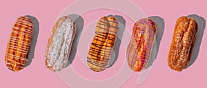 Set of fresh eclairs with original decor on a pink background. banner with trendy hard shadows top view