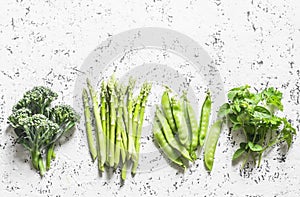 Set of fresh organic green vegetables - broccoli, green peas, asparagus, oregano on a light background. Food background, top view.