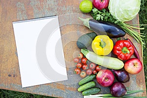 Set of fresh organic vegetables and fruits on rustic wooden table and notebook. Diet plan. Healthy food. Top view. From above.