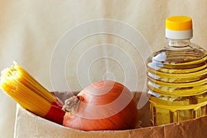 A set of fresh products in a paper bag: a bottle of oil, pasta, onions. Bag food concept