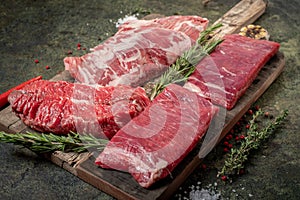 Set of fresh raw alternative beef steaks on a wooden Board: Denver, Skirt, Flank, Machete