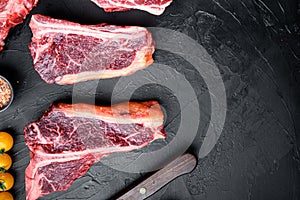 Set of Fresh raw marbled beef steaks, tomahawk, t bone, club steak, rib eye and tenderloin cuts, on black stone background, top