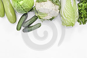 Set of fresh raw organic green vegetables and greens on a white background.