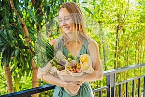 Set of fresh vegetables in a reusable bag in the hands of a young woman. Zero waste concept