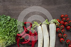 Set of fresh vegetables on a wooden background. Chili pepper, daikon radish, cherry, salad on the table. Place for text