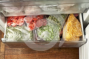 Set of frozen food packed in bags. Store vegetables for the winter in the freezer. Tomato, green peas, corn, greens