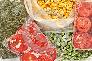 Set of frozen food packed in bags. Store vegetables for the winter, top view. Tomato, green peas, corn, greens