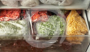 A set of frozen foods for the winter. Frozen berries, vegetables, corn, green peas, tomatoes in the freezer