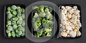 Set of frozen vegetables in containers on a black background. Brussels sprouts, cauliflower, broccoli. View from above