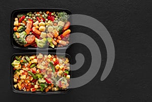 Set of frozen vegetables in containers on a black background. Copy space, view from above