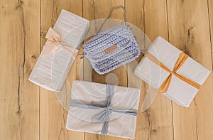 Set of gift boxes with ladies` purse on wooden background. Wrapped in craft paper and tied by cord. Top view