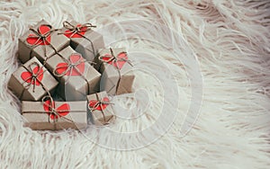 Set of gift boxes wrapped in craft paper and tie hemp string. With cardboard hearts. White fur background.