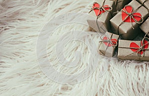 Set of gift boxes wrapped in craft paper and tie hemp string. With cardboard hearts. White fur background. New year.