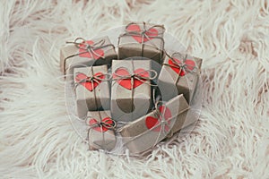 Set of gift boxes wrapped in craft paper and tie hemp string. With cardboard hearts. White fur background. New year.