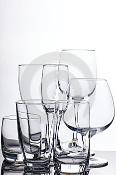 Set of glass empty glasses and goblets on a gray-white background