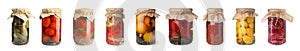 Set of glass jars with different pickled vegetables on background