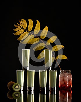 Set of glass shots with green alcoholic drink on black background. Glasses reflected in mirrored table. Composition