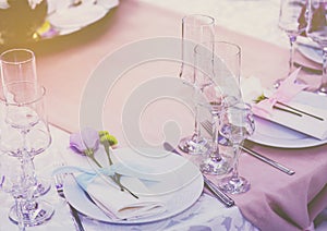 A set of glass of wedding setting with cutlery with a violet flower rose . Table for an event party or wedding reception.