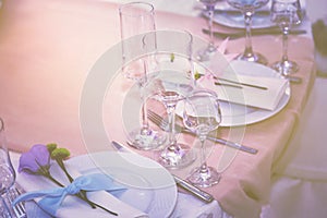 A set of glass of wedding setting with cutlery with a violet flower rose . Table for an event party or wedding reception.