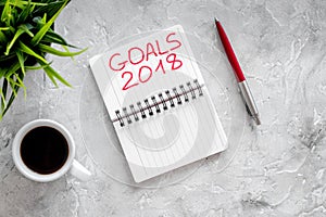 Set a goal for new year 2018. Notebook near pen and cup of coffee on grey stone background top view