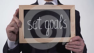 Set goals motivation written on blackboard in businessman hands, success tips