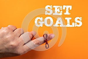 Set Goals. String tired around finger on orange background