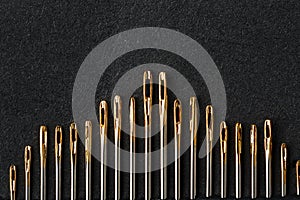 Set of Gold needles on a black background in a row