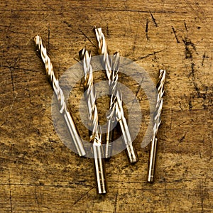 Set of golden drill bits on wooden background