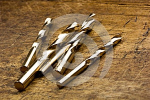 Set of golden drill bits on wooden background