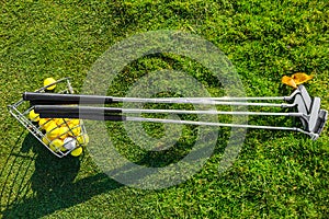 A set of golf clubs and a basket of balls are lying on the green grass