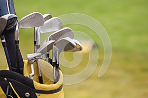 Set of golf clubs over green field