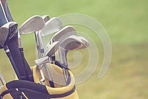 Set of golf clubs over green field