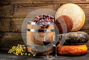 Set of grape, wine and various types of cheese on brown wooden background