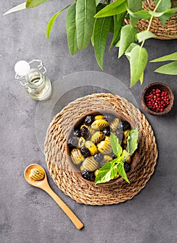 A set of green and black dried olives in bowl on a dark background with olive oil and eucalyptus branch. The concept of vegetarian