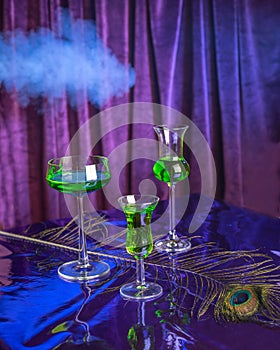 Set of green cocktails with absinthe on a purple background and smoke.