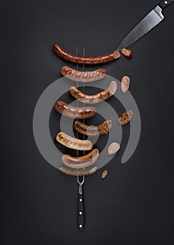 Set of grilled sausages on a fork with cutting knife